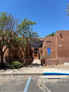 The exterior. The building is brown and adobe, with aesthetically pleasing architecture and black windows.